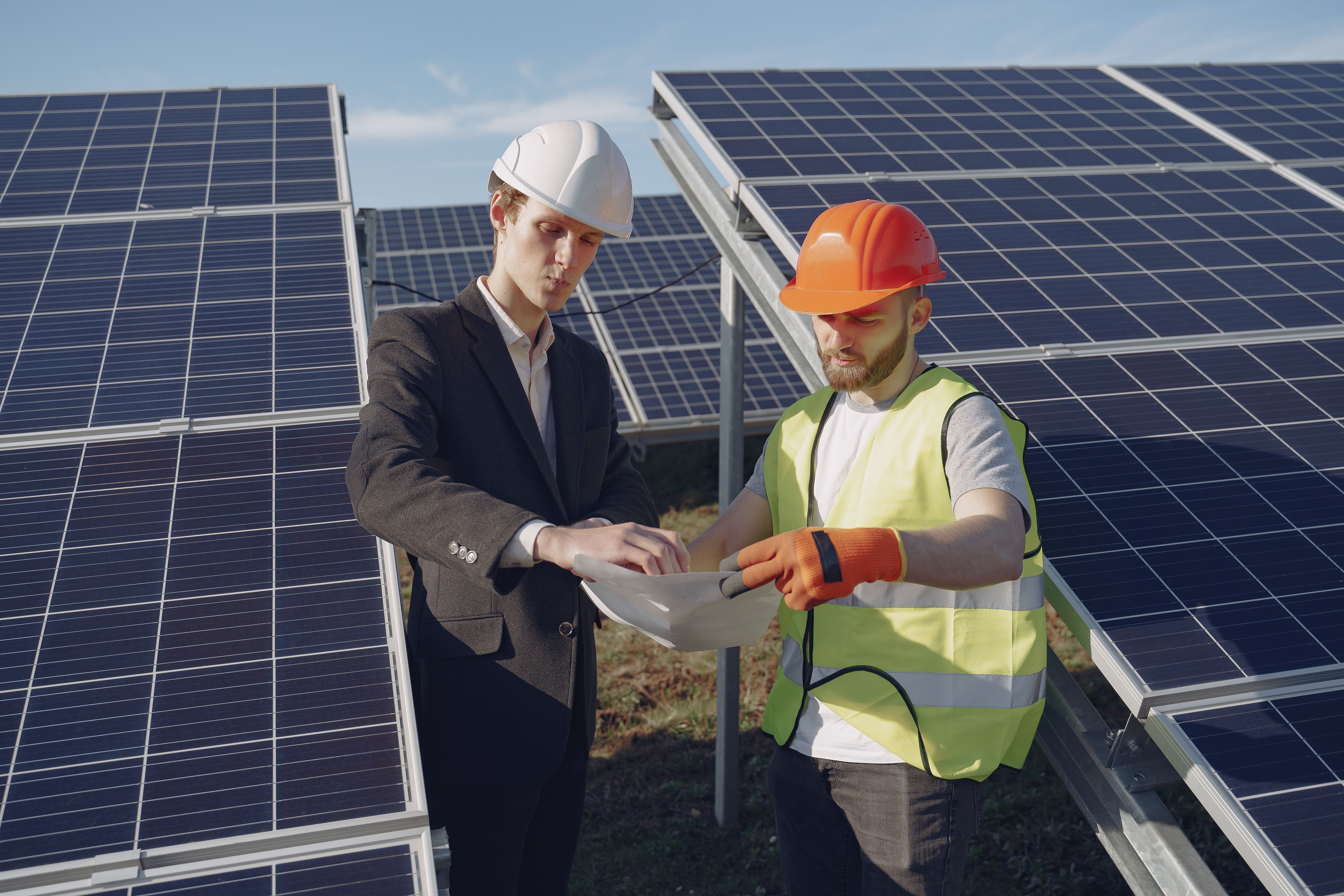 Technik a vedoucí pracovník kontrolují dokumentaci mezi solárními panely
